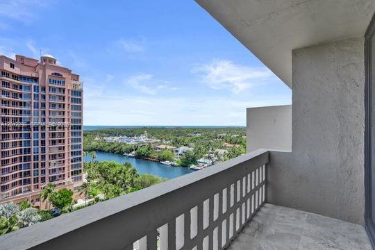 A balcony with a stone floor overlooks a waterway, lush trees, and a tall building — 90 Edgewater # 18, Coral Gables FL 33133, CORAL GABLES, FL