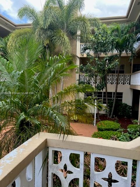 A view from a balcony overlooking lush palm trees and a multi-story apartment building — 1958 Monroe St # 208, Hollywood FL 33020, HOLLYWOOD, FL