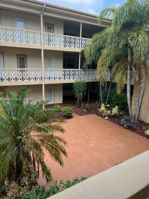 An exterior view of a multi-story apartment building with balconies overlooking a paved courtyard — 1958 Monroe St # 208, Hollywood FL 33020, HOLLYWOOD, FL