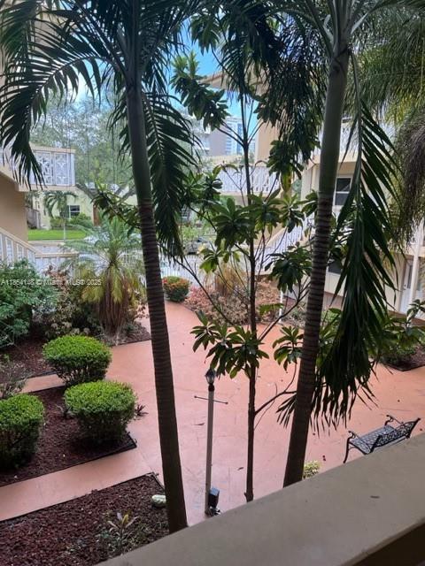 An elevated view of a courtyard with palm trees, landscaped bushes, and a metal bench — 1958 Monroe St # 208, Hollywood FL 33020, HOLLYWOOD, FL