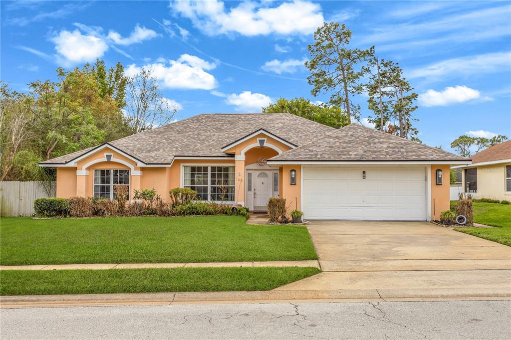 A single-story house with a tan stucco exterior, a two-car garage, and a shingled roof — 105 BREEZEWOOD DRIVE, DEBARY, FL