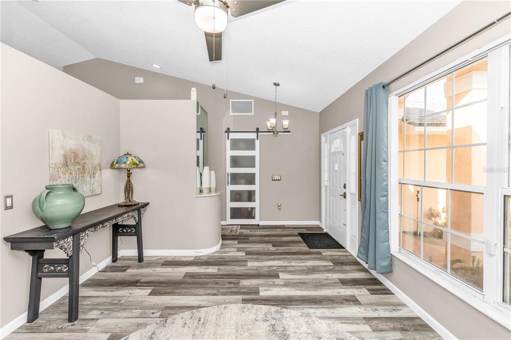 An entryway with wood-look flooring, a console table, a barn door, and a large window — 105 BREEZEWOOD DRIVE, DEBARY, FL