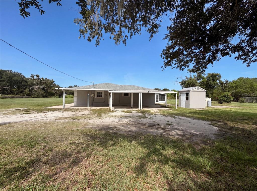 The exterior of a single-story house features a covered patio and a detached storage shed — 2805 105TH STREET E, PALMETTO, FL