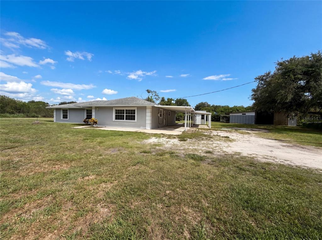 A single-story gray house with a carport sits on a large, grassy lot — 2805 105TH STREET E, PALMETTO, FL