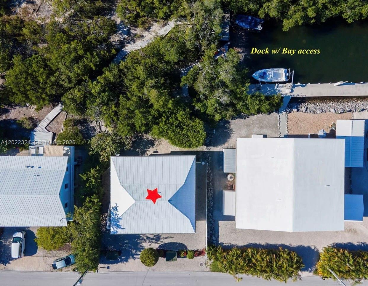 An aerial view shows three buildings, a dock with a boat, and surrounding vegetation — 102 Venetian Dr # 102, Islamorada FL 33036, ISLAMORADA, FL