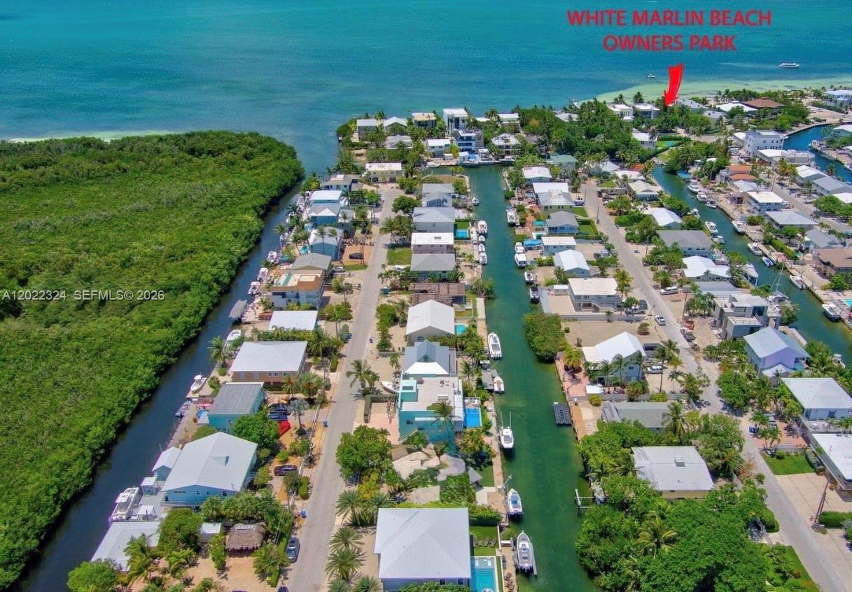 An aerial view shows a coastal residential neighborhood with a canal and a beach park — 102 Venetian Dr # 102, Islamorada FL 33036, ISLAMORADA, FL