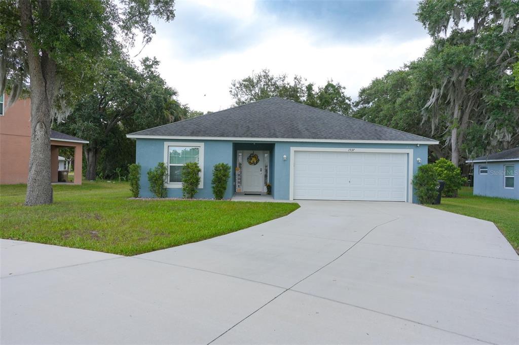 A blue single-story house with a two-car garage and a concrete driveway — 1537 BAYWOOD VILLAGE COURT, MOUNT DORA, FL