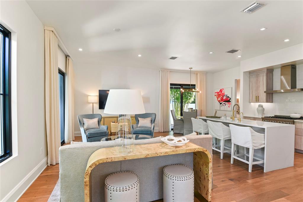 An open-concept living room and kitchen featuring a central island, blue armchairs, and wood flooring — 1120 WISCONSIN AVENUE, WINTER PARK, FL