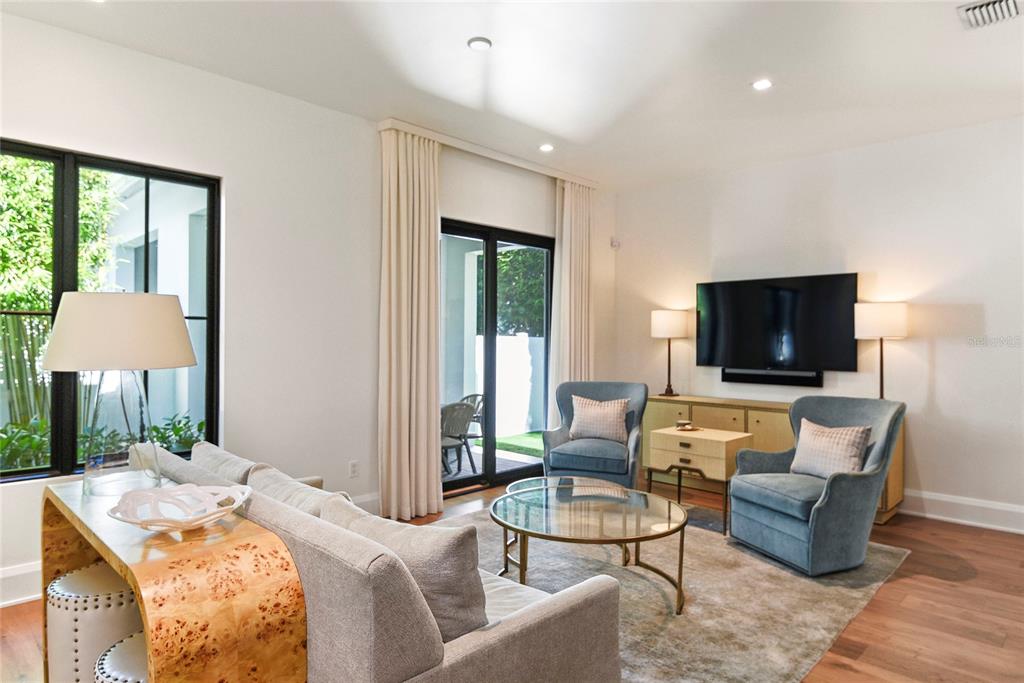 A living room features a sofa, two blue armchairs, a television, and glass sliding doors — 1120 WISCONSIN AVENUE, WINTER PARK, FL