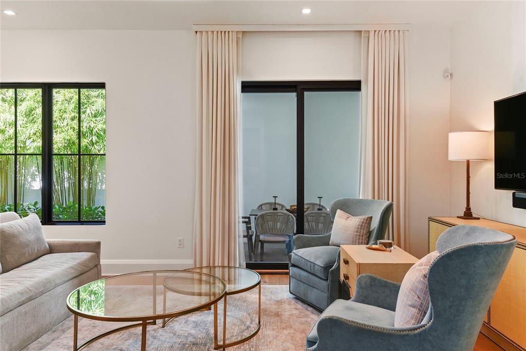 A living room features two blue armchairs, a glass coffee table, and sliding glass doors — 1120 WISCONSIN AVENUE, WINTER PARK, FL