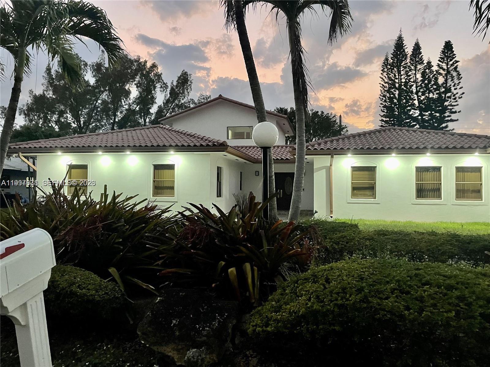 A single-story house with a tiled roof and exterior lighting at dusk — 19740 W Saint Andrews Dr, Hialeah FL 33015, HIALEAH, FL