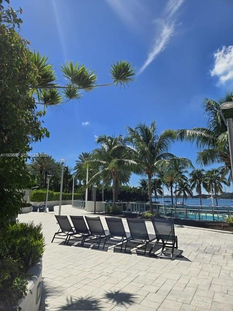 A paved pool deck features lounge chairs overlooking a waterfront view with palm trees — 1500 Bay Rd # 1178S, Miami Beach FL 33139, MIAMI BEACH, FL