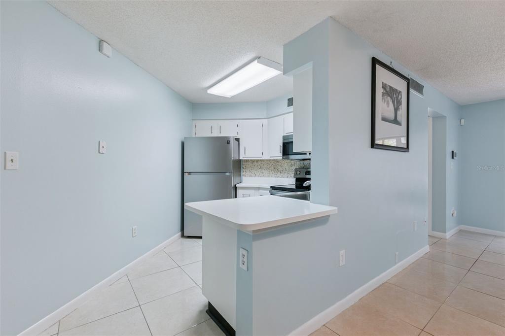 A kitchen with white cabinets, stainless steel appliances, and a breakfast bar — 3685 ATRIUM DRIVE UNIT L1, ORLANDO, FL