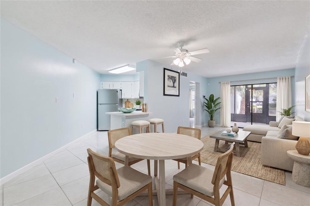 An open-concept living and dining area features light blue walls, tile flooring, and neutral furniture — 3685 ATRIUM DRIVE UNIT L1, ORLANDO, FL