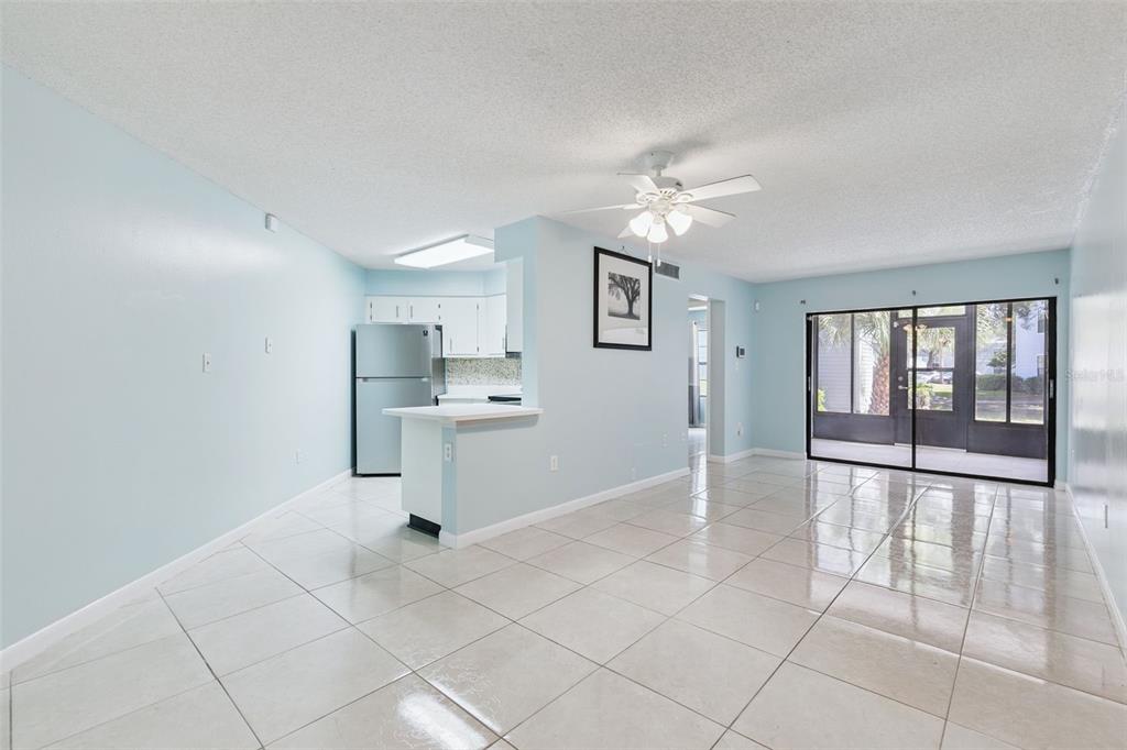 A bright living room with tile floors, a ceiling fan, and an open kitchen area — 3685 ATRIUM DRIVE UNIT L1, ORLANDO, FL