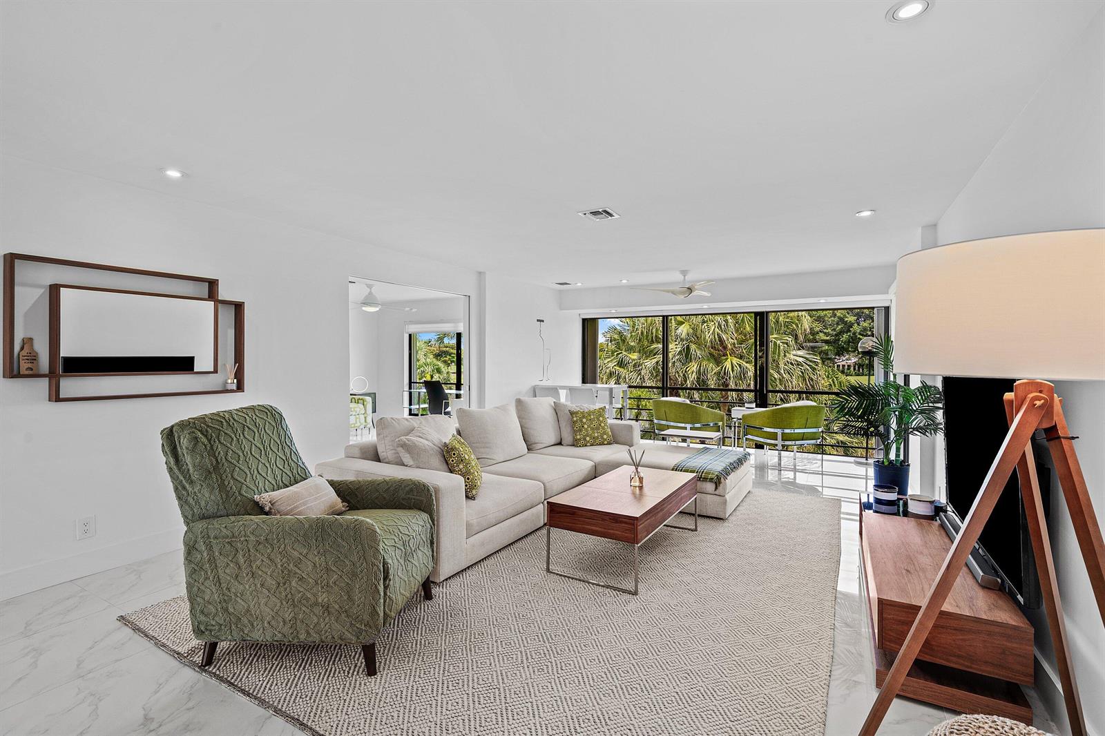 A bright living room features a beige sectional, a green armchair, and floor-to-ceiling windows — 3808 Quail Ridge Drive N, Boynton Beach FL 33436, BOYNTON BEACH, FL
