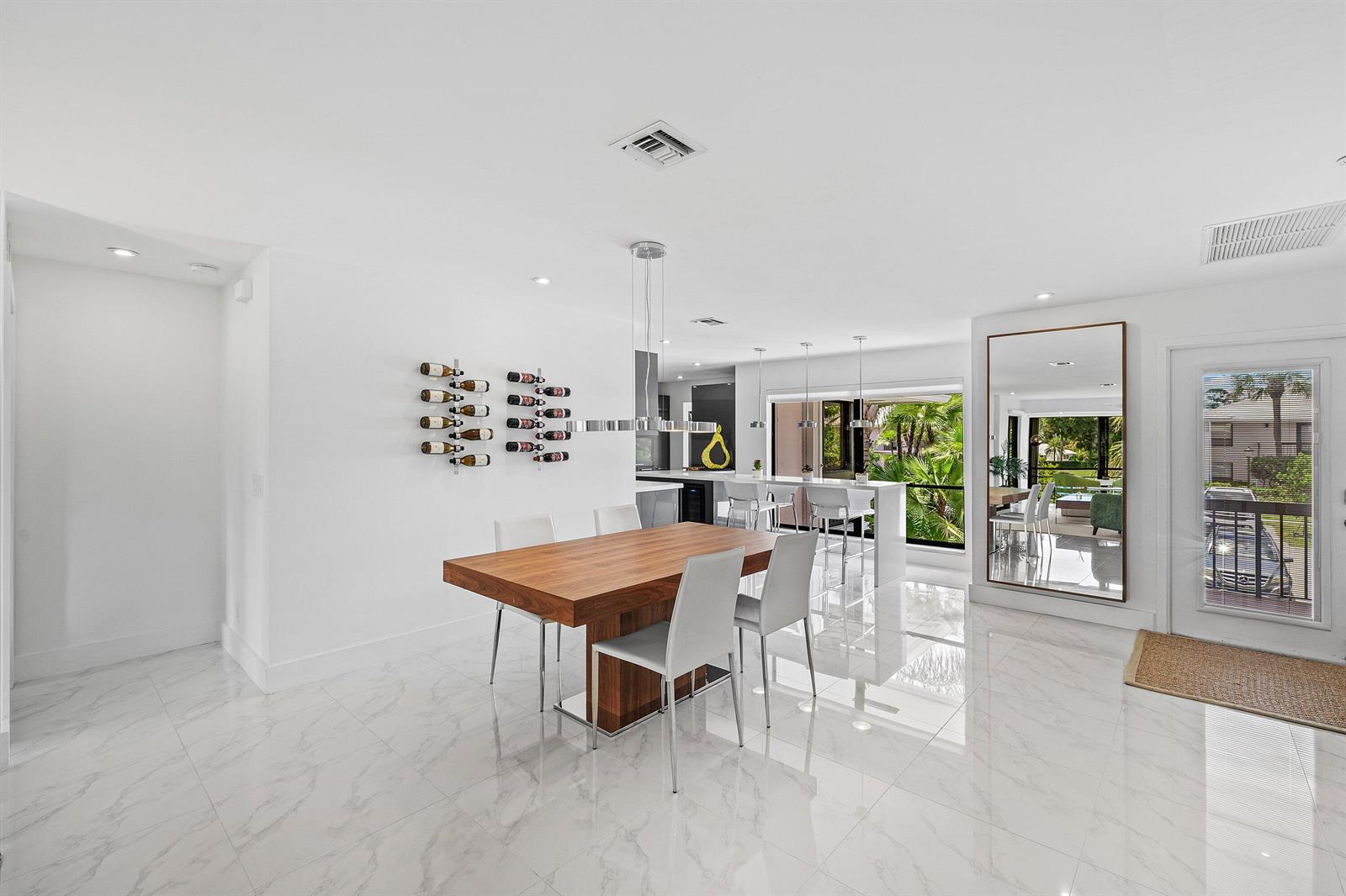 A dining area features a wooden table, white chairs, wall-mounted wine racks, and marble flooring — 3808 Quail Ridge Drive N, Boynton Beach FL 33436, BOYNTON BEACH, FL