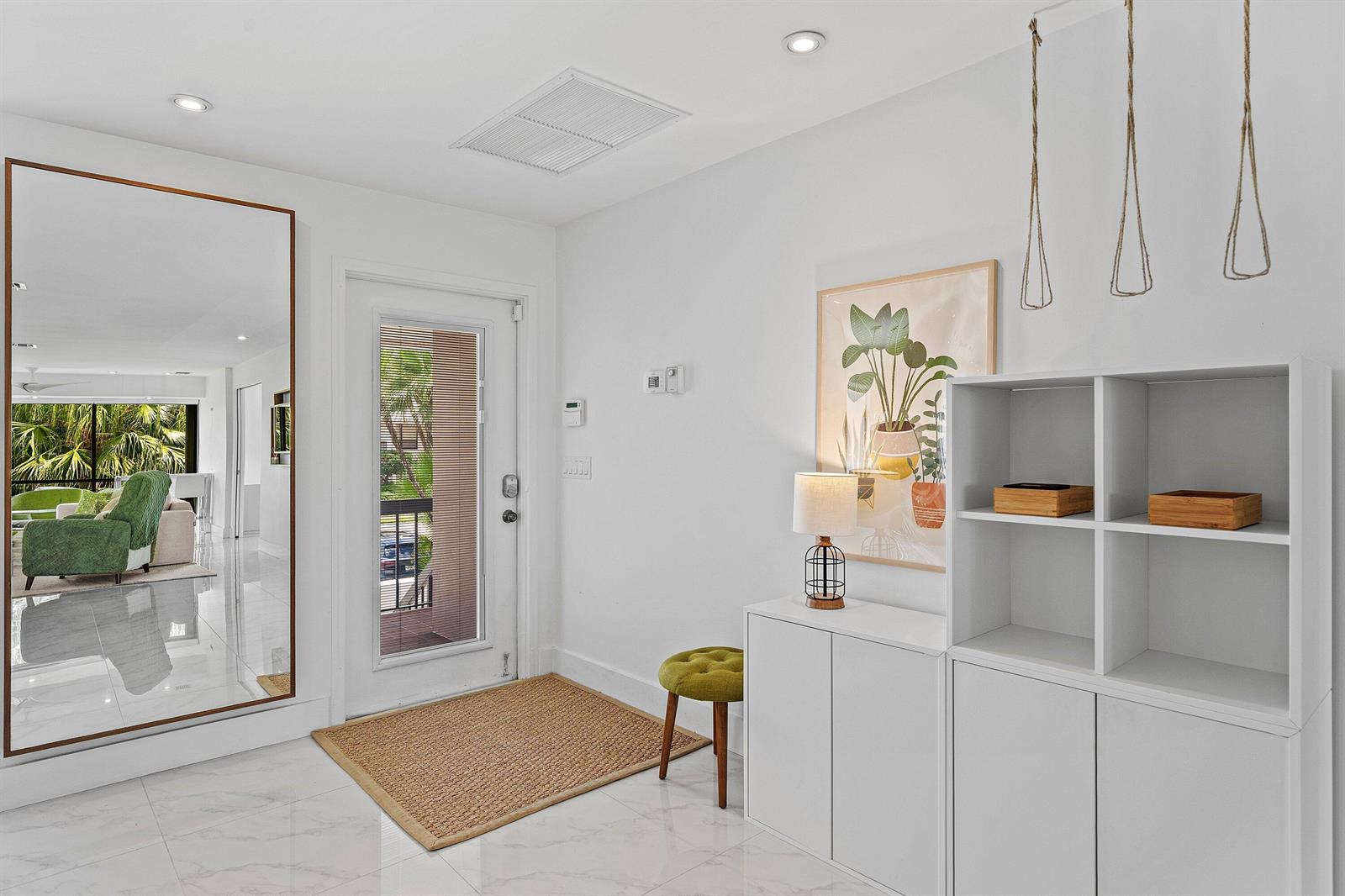 A bright entryway features white walls, marble flooring, a large mirror, and storage furniture — 3808 Quail Ridge Drive N, Boynton Beach FL 33436, BOYNTON BEACH, FL