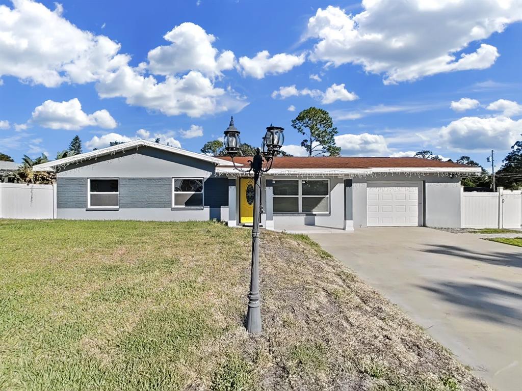 A single-story gray house with a yellow front door, a garage, and a lamp post — 1837 AUDREY DRIVE, CLEARWATER, FL