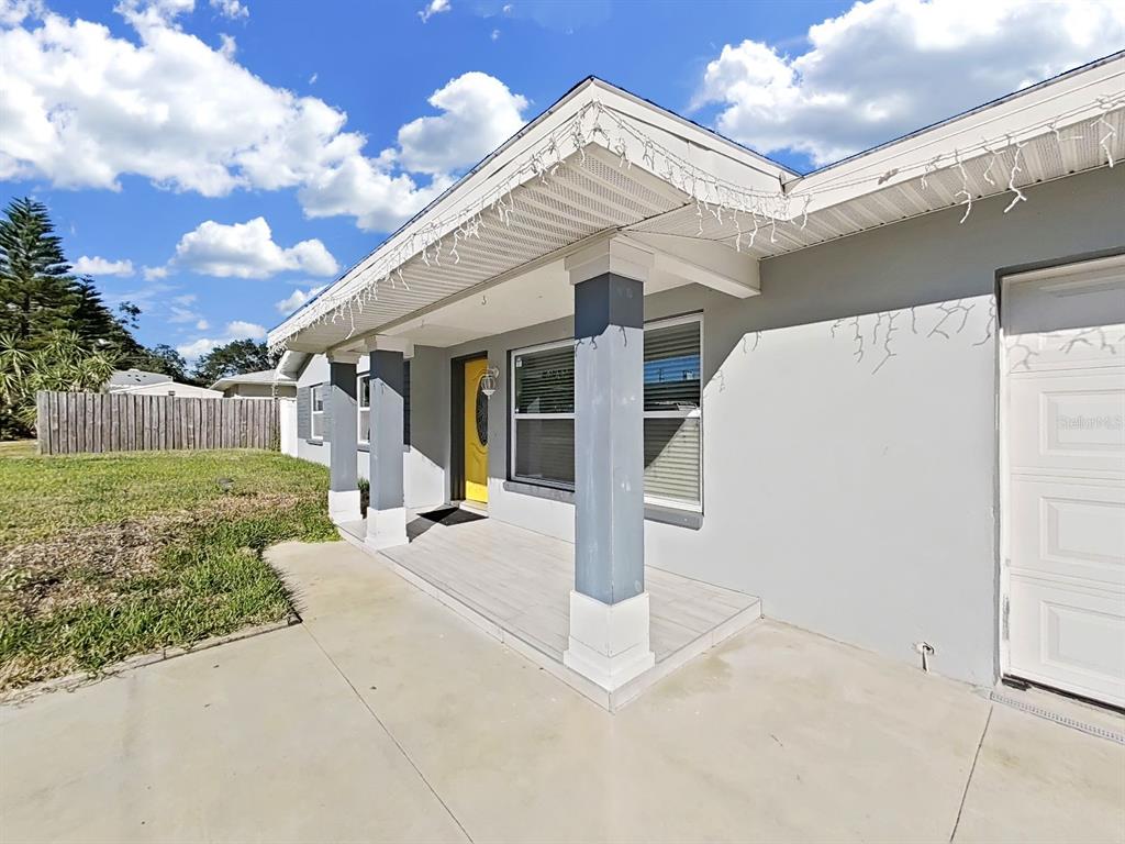 A gray house exterior features a covered front porch with columns and a yellow door — 1837 AUDREY DRIVE, CLEARWATER, FL