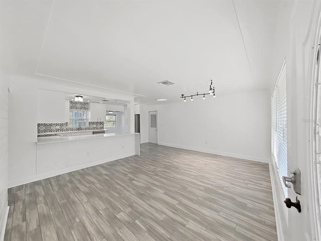 An open-concept living room with light wood-look flooring and a kitchen with a breakfast bar — 1837 AUDREY DRIVE, CLEARWATER, FL