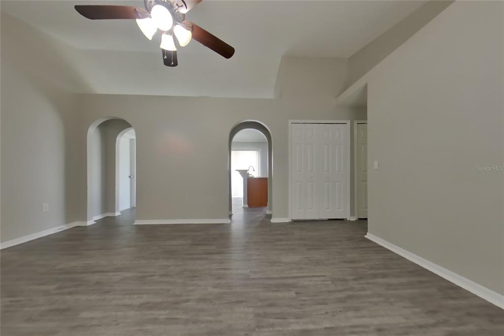 A living room with gray walls, wood-look flooring, arched doorways, and a ceiling fan — 353 COMFORT DRIVE, APOPKA, FL