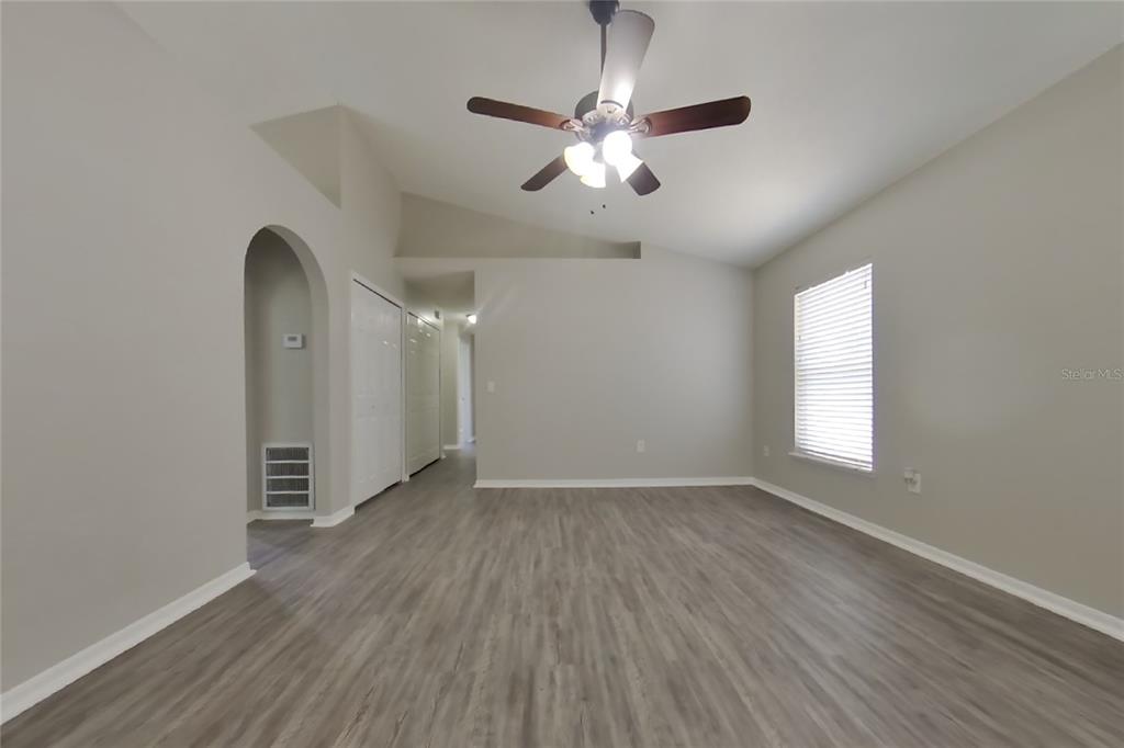 An empty room with light gray walls, wood-look flooring, a ceiling fan, and an arched doorway — 353 COMFORT DRIVE, APOPKA, FL