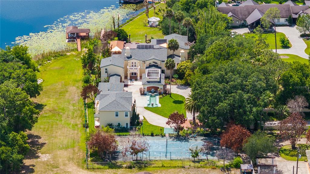 An aerial view shows a large house with a tennis court, fountain, and lake access — 8866 DARLENE DRIVE, ORLANDO, FL