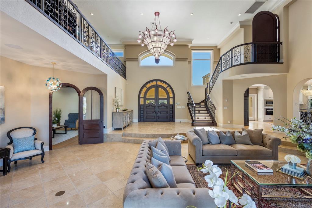 A grand foyer features a high ceiling, a large chandelier, stone floors, and a staircase — 8866 DARLENE DRIVE, ORLANDO, FL