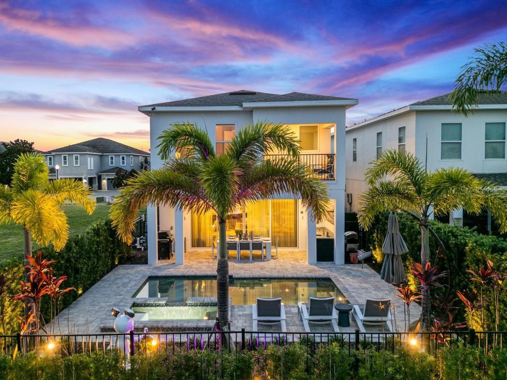 A two-story house exterior features a backyard swimming pool, patio dining area, and palm trees — 1117 CASTLE PINES COURT, REUNION, FL