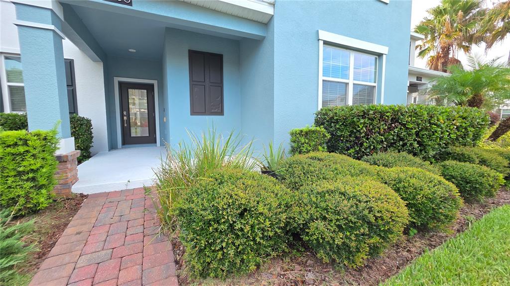 The exterior of a blue house features a brick walkway leading to a front entrance — 11883 PULITZER PLACE, ORLANDO, FL