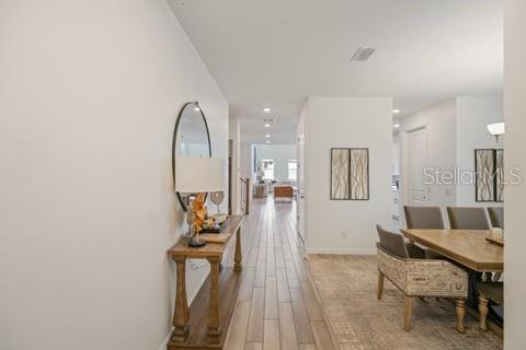 A hallway with light wood-look tile flooring leads toward an open-concept living and dining area — 2099 DERWENT DRIVE, DAVENPORT, FL