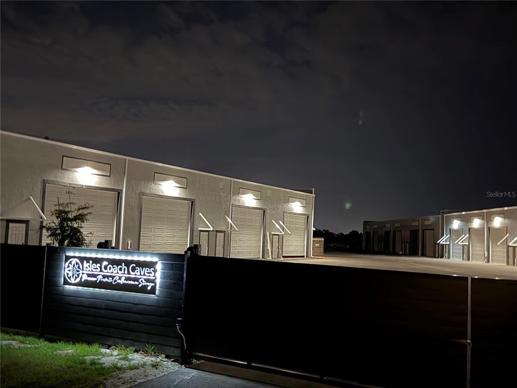 The exterior of a storage facility features illuminated signage and multiple garage doors at night — 4017 TAYLOR ROAD UNIT D3or 6, PUNTA GORDA, FL
