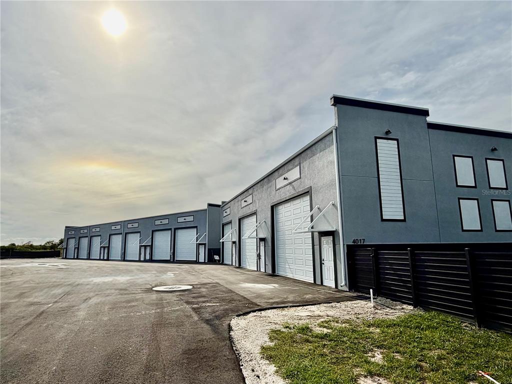 A row of gray industrial warehouse units with roll-up doors and pedestrian entrances — 4017 TAYLOR ROAD UNIT D3or 6, PUNTA GORDA, FL
