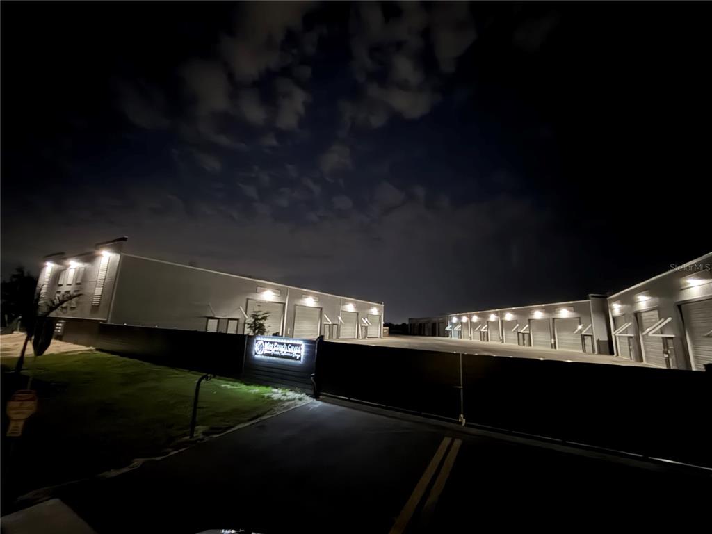 An exterior night view of a commercial storage facility with multiple roll-up garage doors — 4017 TAYLOR ROAD UNIT D3or 6, PUNTA GORDA, FL