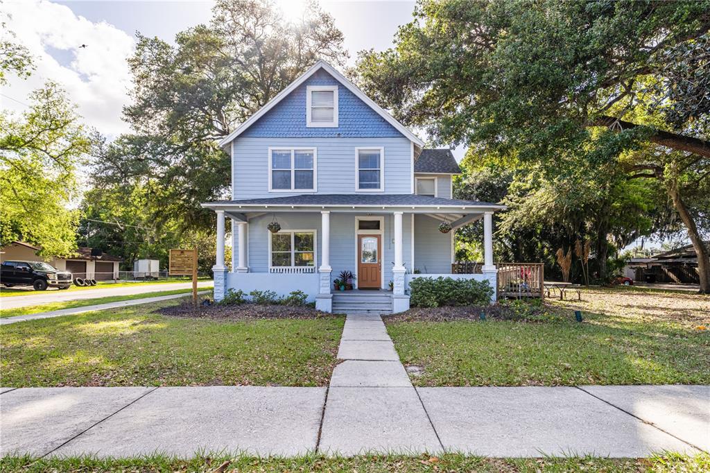 A two-story blue house with a front porch sits on a grassy corner lot — 1320 JERSEY AVENUE, ST CLOUD, FL
