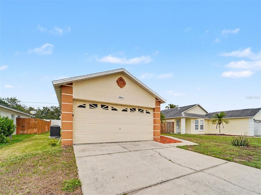 A single-story house with a beige stucco exterior, a two-car garage, and a concrete driveway — 10236 FLAGSHIP AVENUE, PORT RICHEY, FL