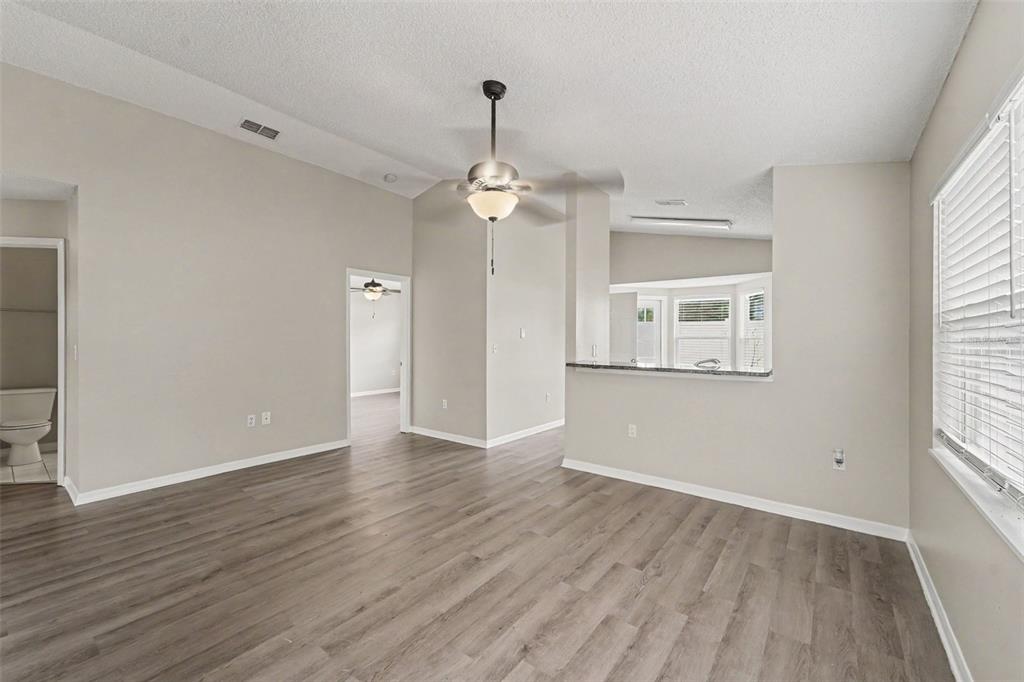 A living room with light gray walls, wood-look flooring, a ceiling fan, and a pass-through — 10236 FLAGSHIP AVENUE, PORT RICHEY, FL