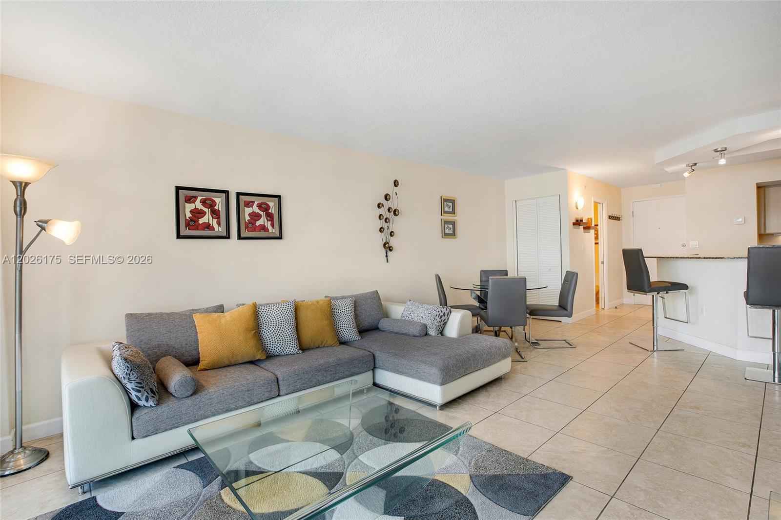 A living room features a gray sectional sofa, a glass coffee table, and a dining area — 6917 Collins Ave # 1608, Miami Beach FL 33141, MIAMI BEACH, FL