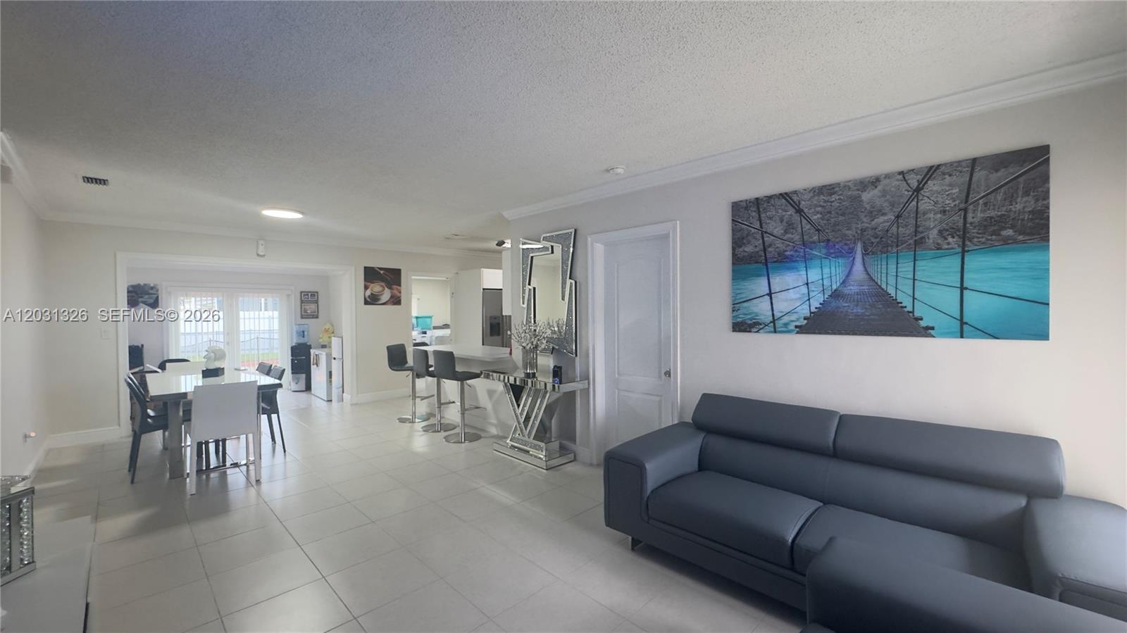 A living and dining area features white tile floors, a dark sofa, and a bridge painting — 12480 SW 189th St, Miami FL 33177, MIAMI, FL