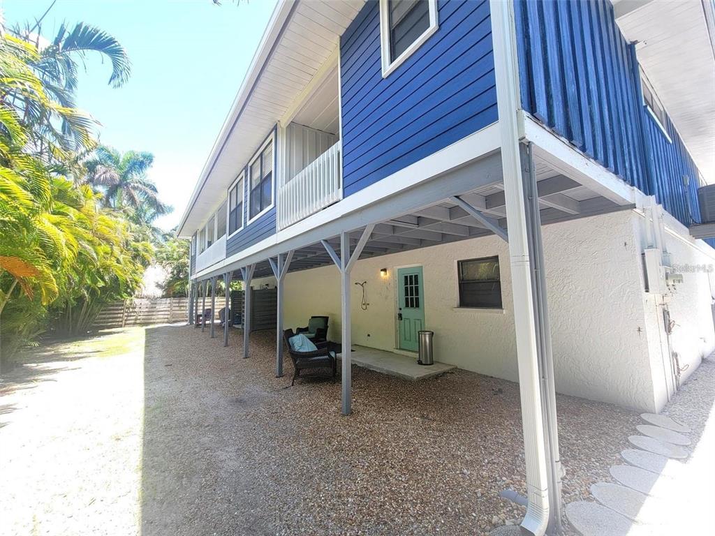 A two-story house with blue siding, a covered ground-level patio, and a gravel yard — 306 63RD STREET UNIT B, HOLMES BEACH, FL