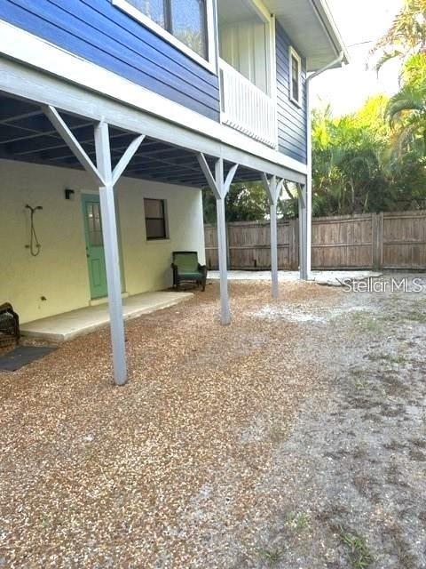 The exterior of a raised house features a gravel yard, a porch, and a green door — 306 63RD STREET UNIT B, HOLMES BEACH, FL