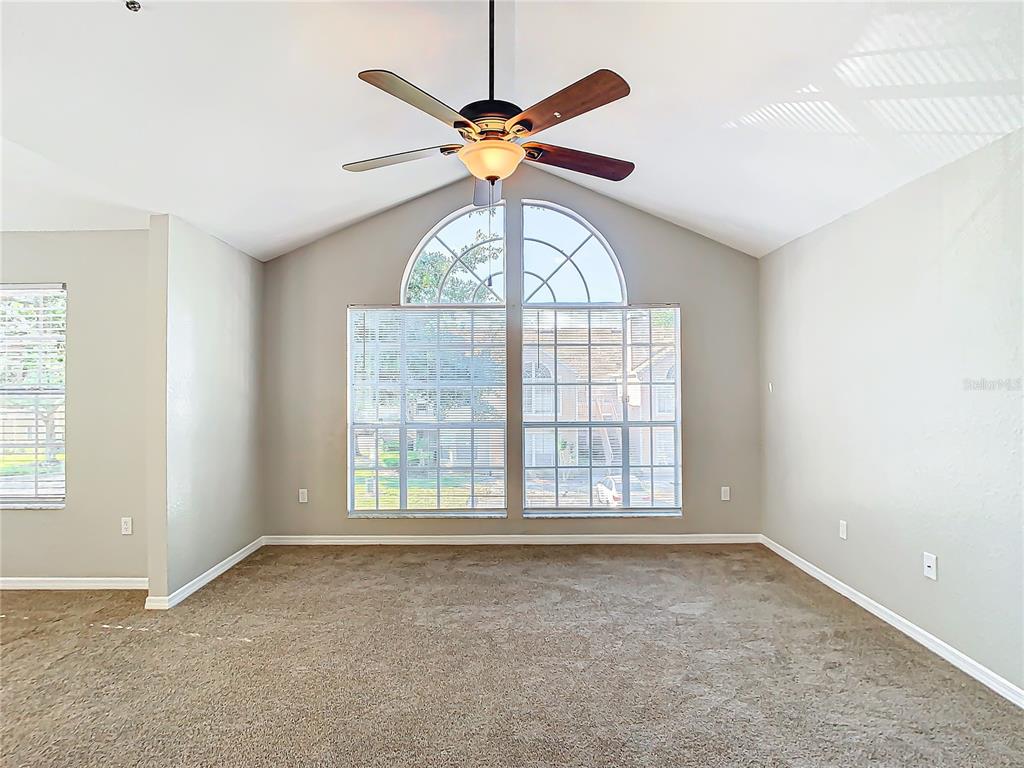 A carpeted living room features a vaulted ceiling, a ceiling fan, and large arched windows — 665 YOUNGSTOWN PARKWAY UNIT 262, ALTAMONTE SPRINGS, FL