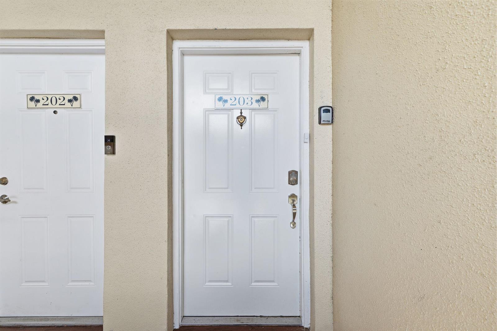 Two white doors labeled 202 and 203 are set into a textured beige exterior wall — 815 Boynton Beach Boulevard # 8203, Boynton Beach FL 33426, BOYNTON BEACH, FL