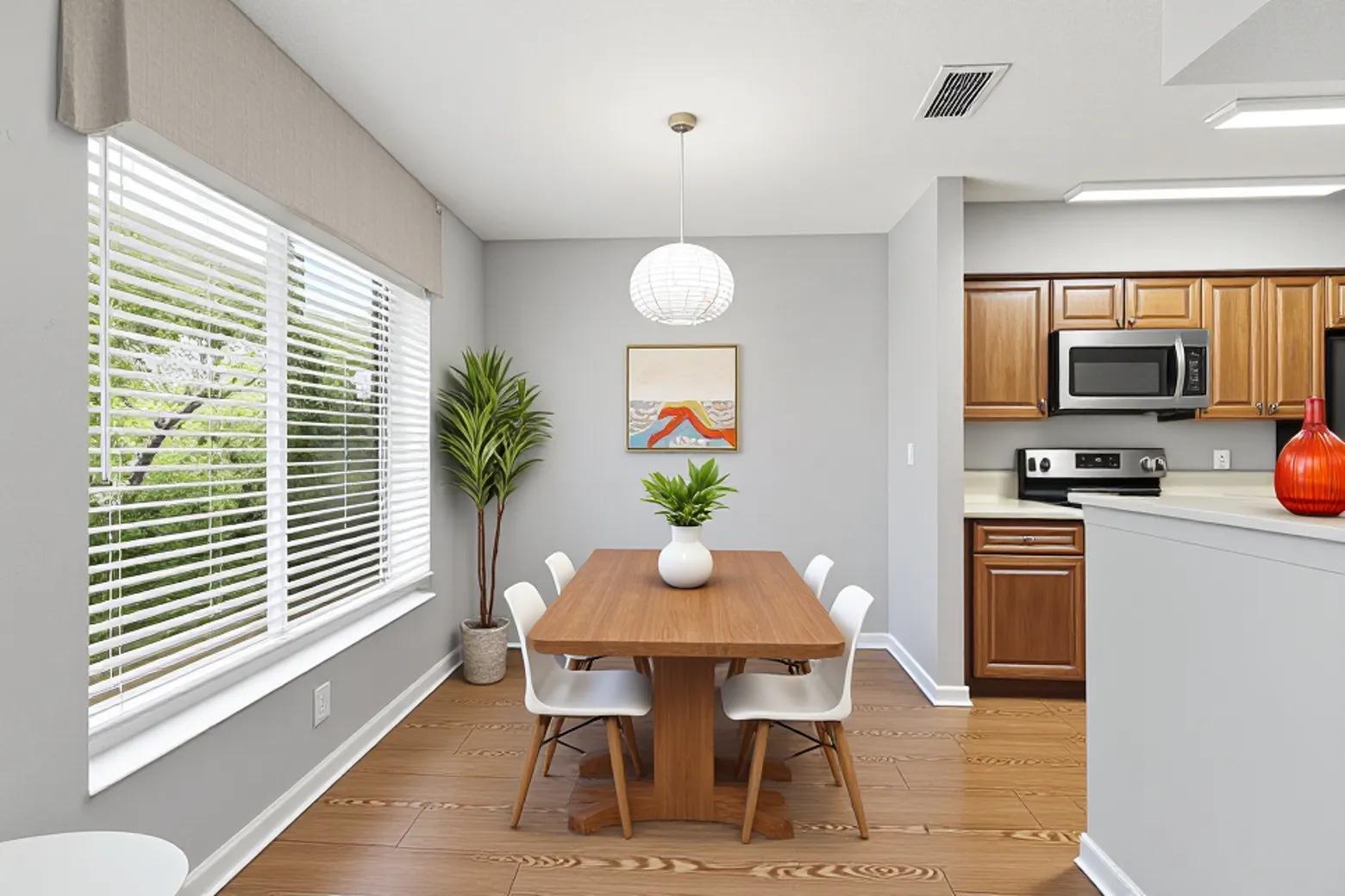 A dining area with a wooden table, white chairs, a pendant light, and adjacent kitchen cabinets — 815 Boynton Beach Boulevard # 8203, Boynton Beach FL 33426, BOYNTON BEACH, FL