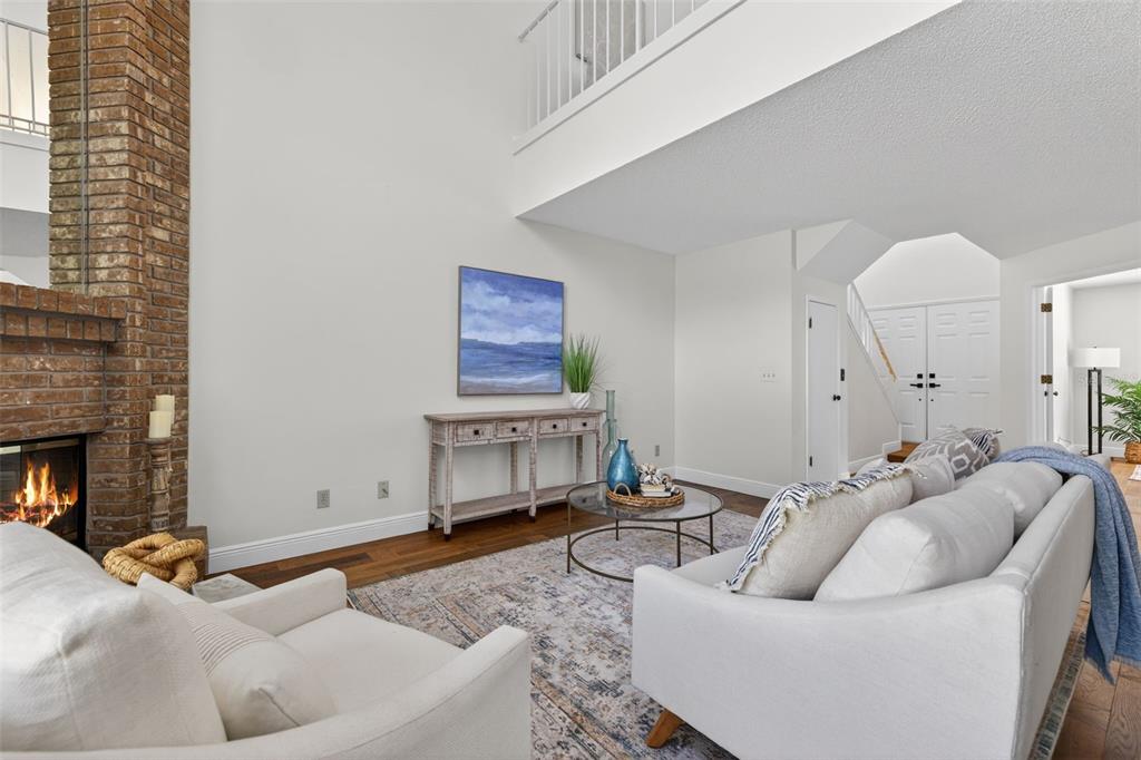 A living room features a brick fireplace, white walls, a console table, and a sofa — 713 CAYA COSTA COURT NE, ST PETERSBURG, FL