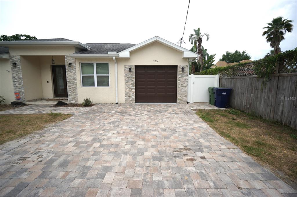 A single-story house exterior features a paved driveway, a brown garage door, and stone accents — 2314 W SAINT SOPHIA STREET, TAMPA, FL