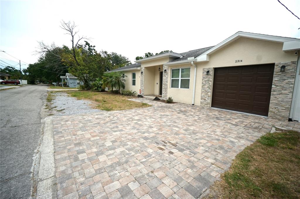 A single-story house with a paved driveway, stone accents, and a brown garage door — 2314 W SAINT SOPHIA STREET, TAMPA, FL