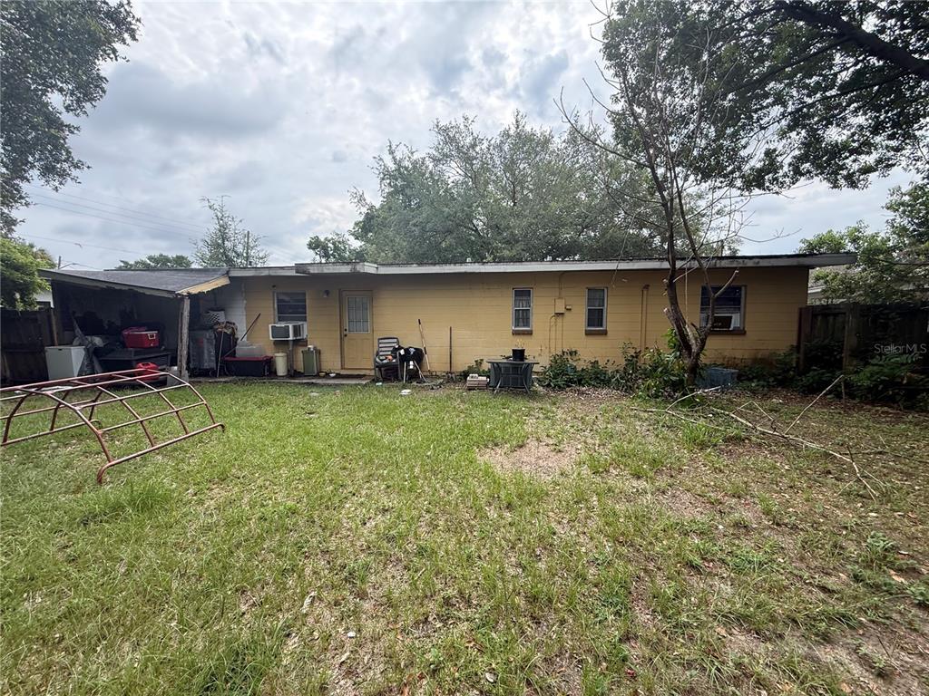 The backyard of a single-story yellow house features a covered patio and a metal climber — 4108 DELRAY AVENUE, ORLANDO, FL