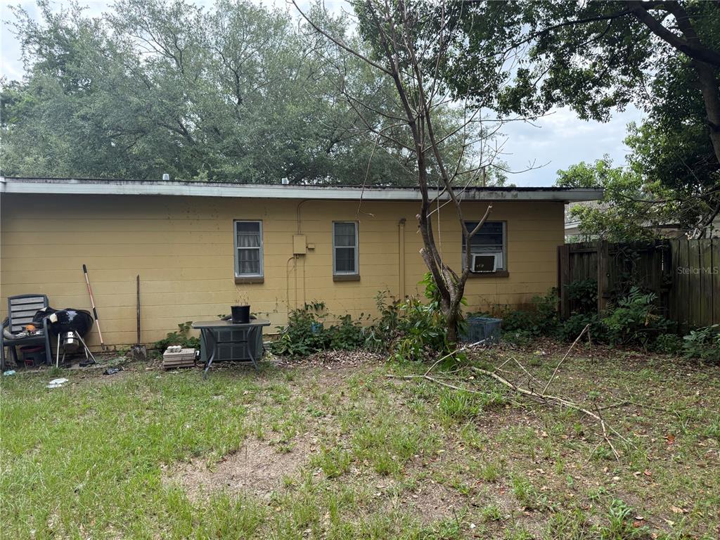 The exterior of a yellow concrete block house features three windows and a wooden fence — 4108 DELRAY AVENUE, ORLANDO, FL